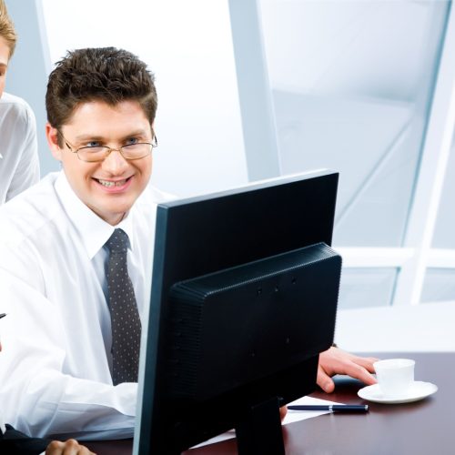 Team of three business people looking at monitor of computer in the office
