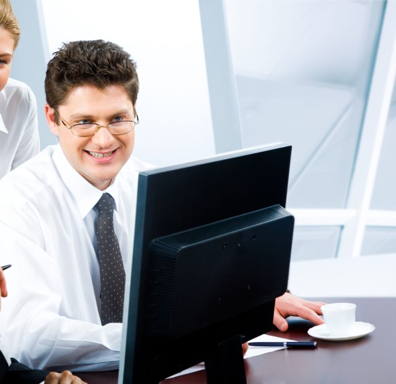 Team of three business people looking at monitor of computer in the office